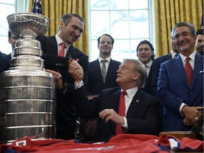 U.S. President Donald Trump (seated) shakes hands with team captain and 2018 playoffs MVP Alex Ovechkin as last season's Stanley Cup champion Washington Capitals visit the Oval Office at the White House with the Stanley Cup in tow in Washington on Monday, March 25, 2019. Capitals owner Ted Leonsis stands to the right with other team members in the background.