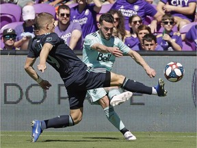 Orlando City's Chris Mueller, left, clears the ball away from Russell Teibert of the VAncouver Whitecaps during Saturday's Major League Soccer match n Orlando, Fla. The Caps lost 1-0.