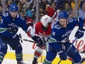 Vancouver Canucks blueliners Ben Hutton (left) and Troy Stecher put the squeeze on Carolina Hurricanes winger Justin Williams during a Jan. 23, 2019 NHL game at Rogers Arena.