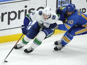 Vancouver Canucks' Troy Stecher skates around the St. Louis Blues' Brayden Schenn during the third period of an NHL game on April 6, 2019, in St. Louis.