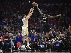 Golden State Warriors guard Klay Thompson, left, shoots as Los Angeles Clippers guard Lou Williams defends during the first half in Game 4 of a first-round NBA basketball playoff series Sunday, April 21, 2019, in Los Angeles.