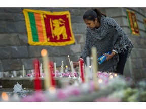 Dharshani Farnando places a candle down as people mourn the deaths from the bombings in Sri Lanka during a vigil at Holland Park in Surrey, BC, April 22, 2019.