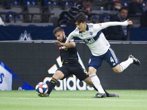 Whitecaps midfielder Inbeom Hwang (right) runs interference on Los Angeles FC’s Diego Rossi during an April MLS game at B.C. Place Stadium.