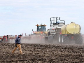 A farmer passes machinery while canola seeds are planted on a farm near St. Francois Xavier, Manitoba, Canada on Thursday, May 9, 2019.