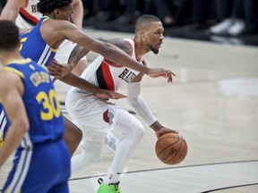 Portland Trail Blazers guard Damian Lillard, right, dribbles past Golden State Warriors center Damian Jones during the first half of Game 3 of the NBA basketball playoffs Western Conference finals Saturday, May 18, 2019, in Portland, Ore.