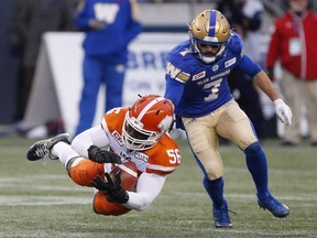 Lions' Solomon Elimimian (left) can't hold onto a pass intended for Blue Bombers' Weston Dressler (right) during the CFL action in Winnipeg on Oct. 28, 2017.