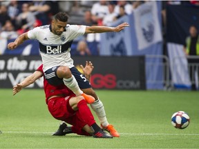Vancouver Whitecaps' Ali Adnan is tackled by Toronto FC's Eriq Zabaleta in a regular season MLS soccer game at B.C. Place on Friday, May 31, 2019.