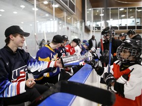 Jack Hughes, left, signs an autograph on a miniature Stanley Cup before a Top Prospects Clinic held Thursday in Vancouver.