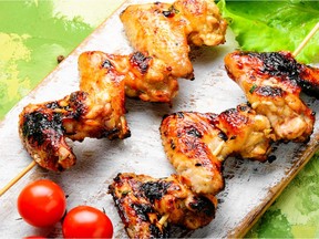 Chicken wings on barbecue grill, cooked on skewers.