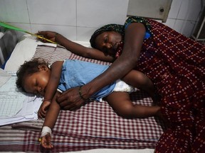 In this picture taken on June 20, 2019, an Indian mother lays next to her child who is suffering from Acute Encephalitis Syndrome (AES), at Kejriwal hospital in Muzaffarpur in the Indian state of Bihar. - From lychees to heat, the factors behind almost 120 children dying in eastern India this month are many. But there are two underlying and preventable root causes: poverty and bad governance. In Bihar state's Hichara, for instance, where the outbreak still rages, there are no toilets, no running water and no cooking gas for the group of thatched huts that make up the village.