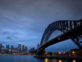 The central business district of Sydney, Australia illuminated at dawn alongside the Harbor Bridge.