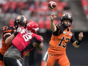 B.C. Lions quarterback Mike Reilly (13) passes as Hunter Steward, back left, holds off Calgary Stampeders' Ese Mrabure during the first half of a pre-season CFL football game in Vancouver on Friday June 7, 2019.