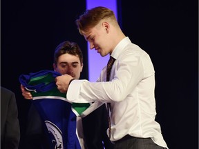 Vasili Podkolzin puts on a jersey after being selected as the number ten overall pick to the Vancouver Canucks in the first round of the 2019 NHL Draft at Rogers Arena.