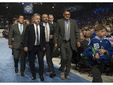 Vancouver Canucks executives walk to the stage during round 1 of the 2019 NHL Draft at Rogers Arena in Vancouver, Friday, June 21.