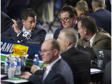 Vancouver Canucks scouting director Judd Brackett talks to GM Jim Benning and AGM John Weisbrod during Day 2 of the 2019 NHL Draft at Rogers Arena.