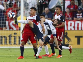 Whitecaps midfielder Jon Erice (in white) kicks the ball away from FC Dallas midfielder Brandon Servania during the first half of their June 26 MLS match at Toyota Stadium in Frisco, Texas.