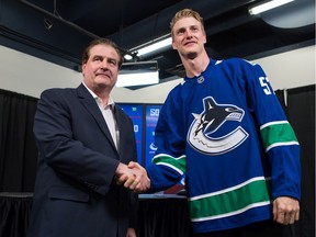 Vancouver Canucks defenceman Tyler Myers, right, and General Manager Jim Benning shakes hands while posing for photos before a news conference after Myers signed a five-year contract with the NHL hockey team, in Vancouver, on Monday July 1, 2019.