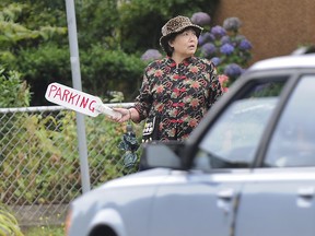 A woman tries to coax drivers into a parking spot in her driveway in east Vancouver, B.C., in this 2008 file photo. (BILL KEAY / PNG)