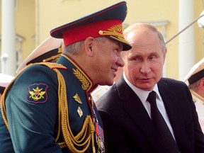 Russian President Vladimir Putin speaks to Defence Minister Sergei Shoigu as they watch the military parade during the Navy Day celebration in St. Petersburg, Russia, July 28, 2019. Dmitri Lovetsky/Pool via REUTERS/File Photo