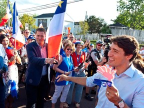 Prime Minister Justin Trudeau points to Conservative Leader Andrew Scheer while walking with the crowd during the Tintamarre in celebration of the National Acadian Day and World Acadian Congress in Dieppe, N.B., on Aug. 15.