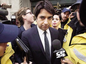 Jian Ghomeshi is escorted by police out of court past members of the media in Toronto on November 26, 2014.