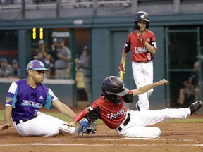 British Columbia's Tai Freeman (4) scores on a wild pitch as Italy's Alex Giovanardi covers the plate during the second inning of a Little League World Series baseball game in South Williamsport, Pa.