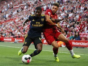 Arsenal's Ainsley Maitland-Niles (left) tries to fend off Liverpool's Alex Oxlade-Chamberlain during their English Premier League game at Anfield in Liverpool on Aug. 24, 2019.