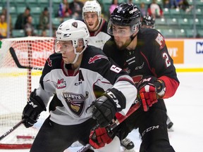 Vancouver Giants defenceman Dylan Plouffe and Prince George Cougars defenceman Cole Moberg battle for a puck Friday in Vancouver's 5-3 win in Prince George to open the WHL season.