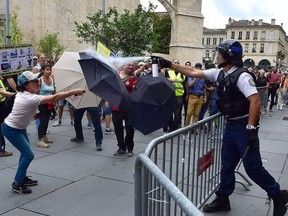 A woman uses an umbrella to shield herself from pepper spray released by a police official during a climate change and 'yellow vest' protest in Bordeaux, south-west France on September 21, 2019, during which a crowd of between 2,000-3,000 marched along the banks of the River Garonne.