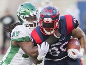 Saskatchewan Roughriders middle linebacker Solomon Elimimian, left, shown tackling the Montreal Alouettes' Spencer Moore, is excelling in his first season with the Green and White.