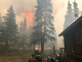 Firefighters from the Chugach National Forest work to protect the Romig Cabin on Juneau Lake from the Swan Lake Fire near Cooper Landing, Alaska, U.S. in this August 28, 2019 handout photo.