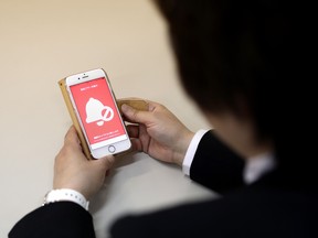 In this picture taken on May 13, 2019, an official at a police department poses as she shows an application for scaring off molesters, in Tokyo.