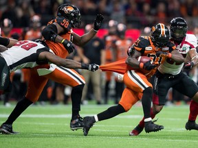B.C. Lions' Brandon Rutley, front run, carries the ball in front of Ottawa Redblacks' Jeff Knox Jr., back right, as Avery Ellis, left, pulls on his jersey in Vancouver on Friday.