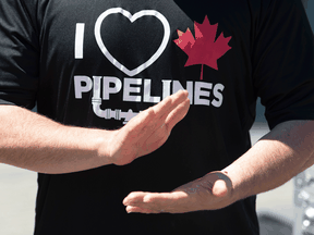A man wearing an "I love Canadian pipelines" shirt applauds during a pro-pipeline gathering in Vancouver.