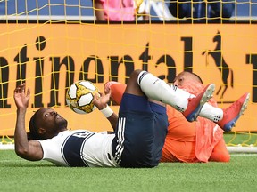 Columbus Crew goalkeeper Eloy Room watches a shot from Vancouver's Theo Bair (not pictured) bounce into his arms in front of Whitecaps forward Tosaint Ricketts during the second half of Saturday's game at B.C. Place.