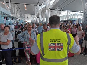A British government official speaks to tourists, flying with Thomas Cook, as they queue at the Enfidha International airport on Monday, on the outskirts of Sousse south of the capital Tunis. - British travel group Thomas Cook on Monday declared bankruptcy after failing to reach a last-ditch rescue deal, triggering the UK's biggest repatriation since World War II to bring back tens of thousands of stranded passengers.