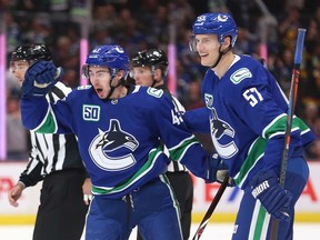 Quinn Hughes of the Vancouver Canucks, left, celebrates his first NHL goal against the Los Angeles Kings on Wednesday with teammate Tyler Myers at Rogers Arena in Vancouver. The Canucks beat the Kings 8-2.