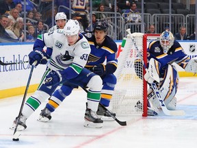 Bo Horvat #53 of the Vancouver Canucks controls the puck against Brayden Schenn #10 and Jordan Binnington #50 of the St. Louis Blues at Enterprise Center on October 17, 2019 in St Louis, Missouri.