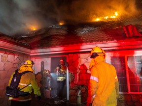 Firefighters enter a burning house as they fight the Saddleridge Fire in the Porter Ranch section of Los Angeles, California, early Oct. 11, 2019, 2019. (DAVID MCNEW/AFP via Getty Images)