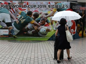 A woman walks past a Rugby World Cup billboard in the Shinagawa district of Tokyo, Japan, October 12, 2019, after matches were cancelled today due to Typhoon Hagibis. REUTERS/Kevin Coombs
