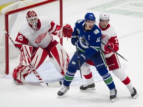 Vancouver Canucks Bo Horvat is pressured by Detroit Red Wings defenceman Dennis Cholowski as he tries to clear him from in front of Jonathan Bernier at Rogers arena, Vancouver, October 15, 2019.