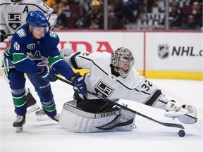 Los Angeles Kings' Jonathan Quick tries to cover up the puck as the Vancouver Canucks' Elias Pettersson tries to steal it.