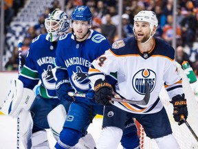 Edmonton Oilers' Zack Kassian holds the stick of former Canuck Ben Hutton as they battle for position in front of Vancouver goalie Jacob Markstrom during NHL action last year.