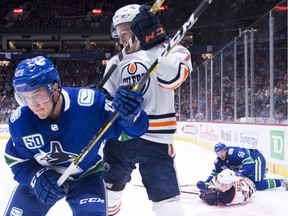 Vancouver Canucks defenceman Ashton Sautner (29) fights for control of the puck with Edmonton Oilers centre Ryan McLeod (70) during first period NHL preseason action in Vancouver, Tuesday, September, 17, 2019.