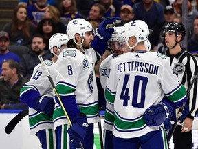 Vancouver Canucks center J.T. Miller  is congratulated by defenseman Christopher Tanev  and centre Elias Pettersson  after scoring during the second period against the St. Louis Blues at Enterprise Center.