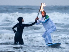 Sarah Muhall hands the Olympic torch to surfer Raphael Bruhwiler during the Vancouver 2010 Torch Relay  at Long Beach in Pacific Rim National Park in 2009.