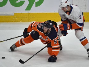 Edmonton Oilers Connor McDavid (97) gets tripped up by New York Islanders Adam Pelech (3) during NHL action at Rogers Place in Edmonton, February 21, 2019.