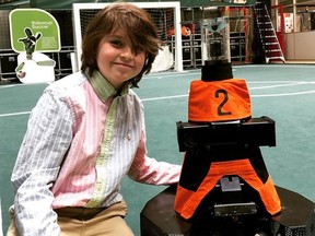 Laurent Simons, 9, poses with a small robot. He will be the youngest person to ever graduate university and is already fielding multiple graduate and PhD offers.
