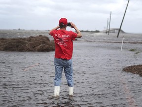 Mike Rogers takes a photo of the storm surge from Hurricane Dorian that blocks Cedar Island off from the mainland on NC 12 in Atlantic, N.C., after Hurricane Dorian passed the coast on Friday, Sept. 6, 2019. (AP Photo/Tom Copeland)