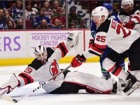New Jersey Devils defenseman Mirco Mueller (25) and goaltender Mackenzie Blackwood (29) reach for the puck against the Vancouver Canucks during the first period at Rogers Arena.